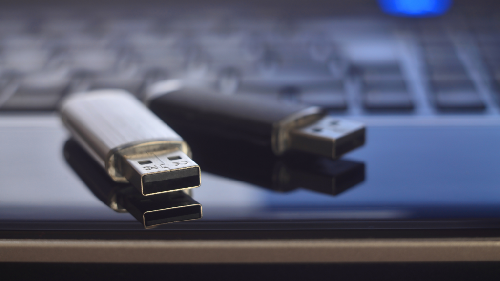 Zwei USB-Sticks in einem Arbeitsumfeld auf einem Laptop.